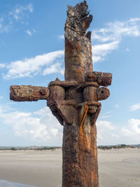 Low angle view of old rusty column against sky