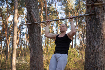 Young man exercising against trees in forest