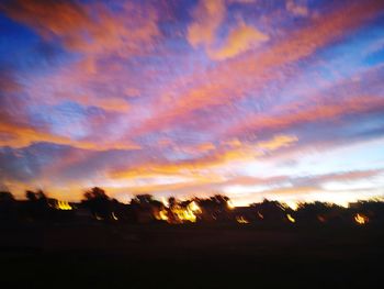 Low angle view of silhouette trees against dramatic sky