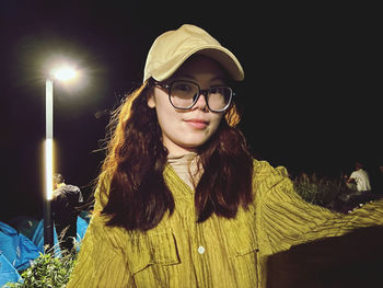 Portrait of woman wearing sunglasses while standing against black background