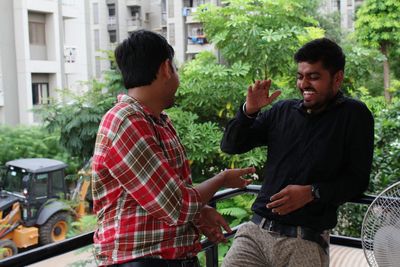 Cheerful male friends high-fiving while standing at balcony