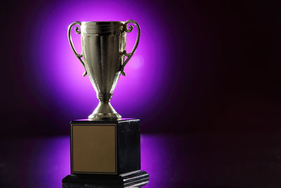 Close-up of trophy against purple light