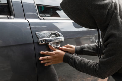 Midsection of man holding cigarette on car