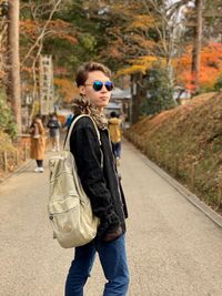 Man with umbrella walking on street amidst trees