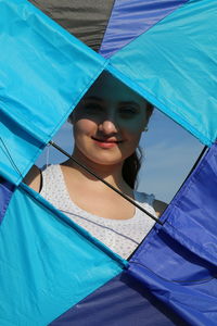 Portrait of smiling young woman looking through kite