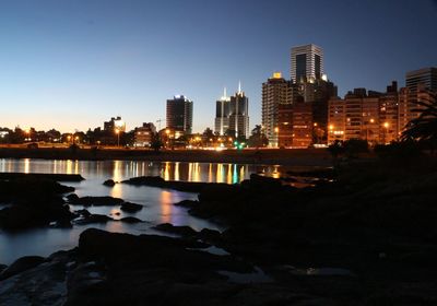 Illuminated cityscape against clear sky at night