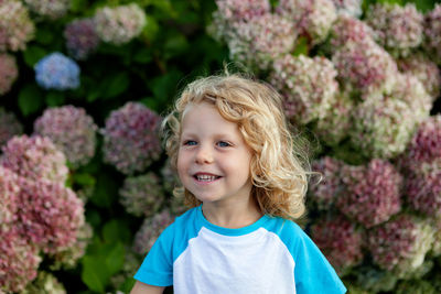 Smiling girl looking away while standing against plants