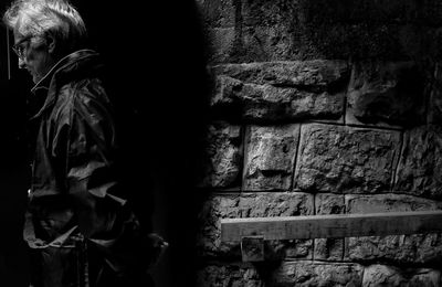 Side view of mature man standing against wall at night