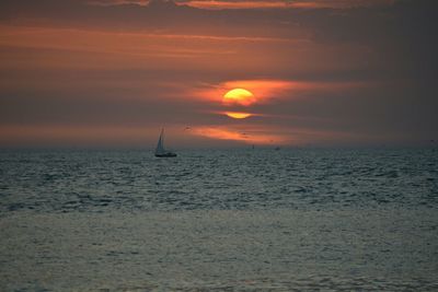 Sailboat sailing in sea against sky during sunset