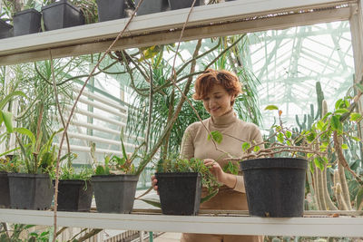 A beautiful plus size young woman takes care of plants green plants in the greenhouse. 