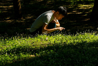 Side view of man touching plant at park