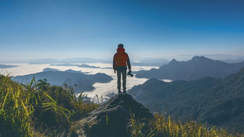 Rear view of man standing on mountain against sky