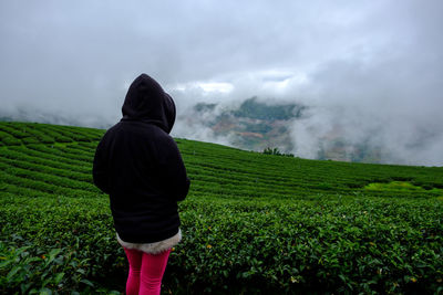 Rear view of woman standing by agricultural field