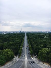 Road passing through city against sky