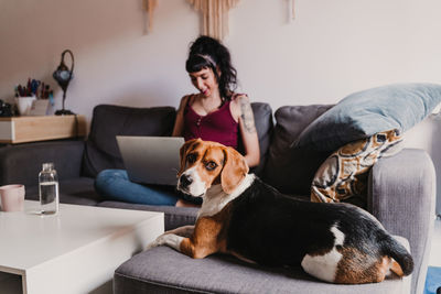 Woman with dog sitting on sofa at home