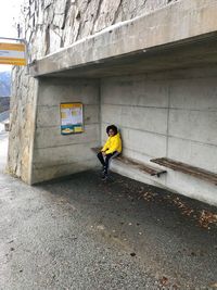 Portrait of boy sitting on seat against wall