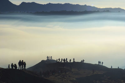 Silhouette people on mountain against sky