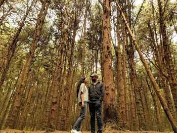 Low angle view of smiling man and woman standing in forest