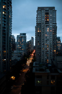 Illuminated buildings in city against sky at dusk