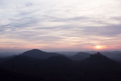 Scenic view of silhouette mountains against dramatic sky