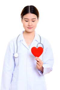 Portrait of a smiling young woman holding heart shape over white background