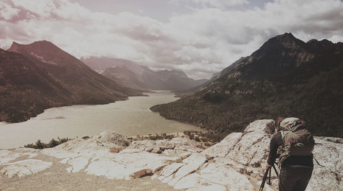 Rear view of woman photographing mountains against cloudy sky