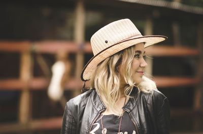 Close-up of young woman wearing hat against stable