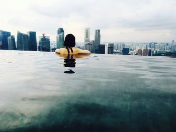 Rear view of woman swimming in infinity pool in sea