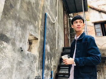 Portrait of young man standing against wall