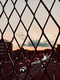 Close-up of chainlink fence against sky during sunset