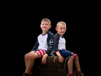 Portrait of boy sitting against black background