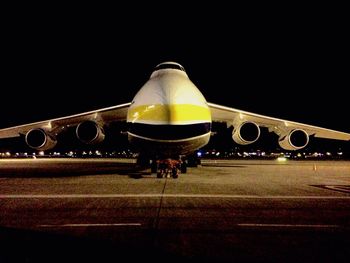 Airplane on airport runway against clear sky at night