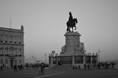 People with equestrian statue of king jose i at praca do comercio against sky