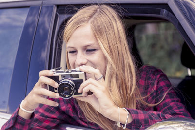 Young woman using mobile phone while sitting in car