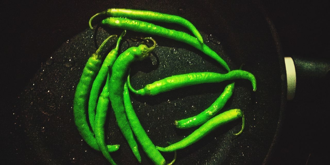 HIGH ANGLE VIEW OF GREEN CHILI PEPPERS AGAINST BLACK BACKGROUND