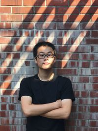 Portrait of man standing against brick wall