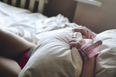 Midsection of mid adult woman holding pillow while lying on bed at home