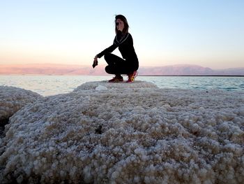 Full length of woman on beach against sky during sunset