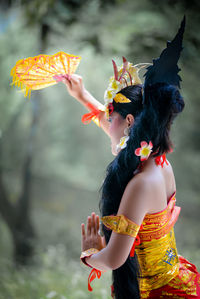 Side view of woman holding flower