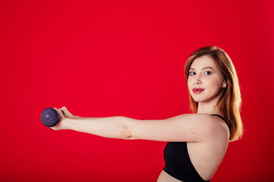 Portrait of smiling young woman against red background