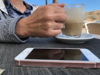 Midsection of man holding coffee cup on table