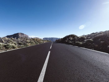 Surface level of road against clear blue sky