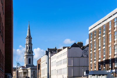 Buildings in city against blue sky on sunny day