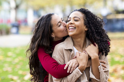 Woman kissing friend in park