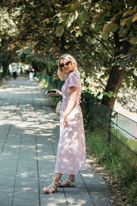 Full length of woman standing on footpath in park