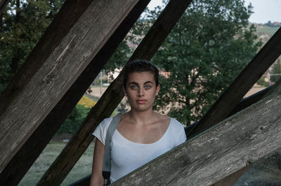 Portrait of young woman standing by tree