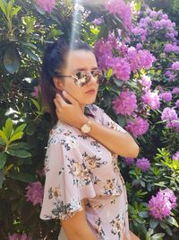 Portrait of beautiful woman standing by flowering plant