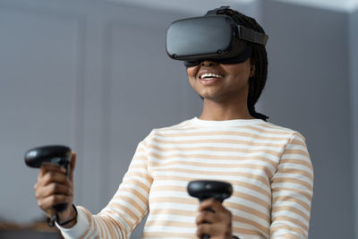 Happy young african woman playing vr games, enjoying gaming experience in virtual reality at home