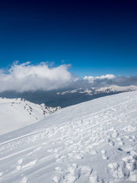 Snow covered landscape against blue sky