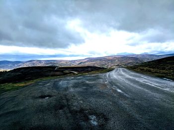 Road leading towards mountains against sky